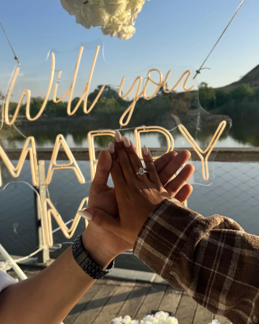 טבעת האירוסין על ידה של הכלה, מול שלט ניאון Will you marry me